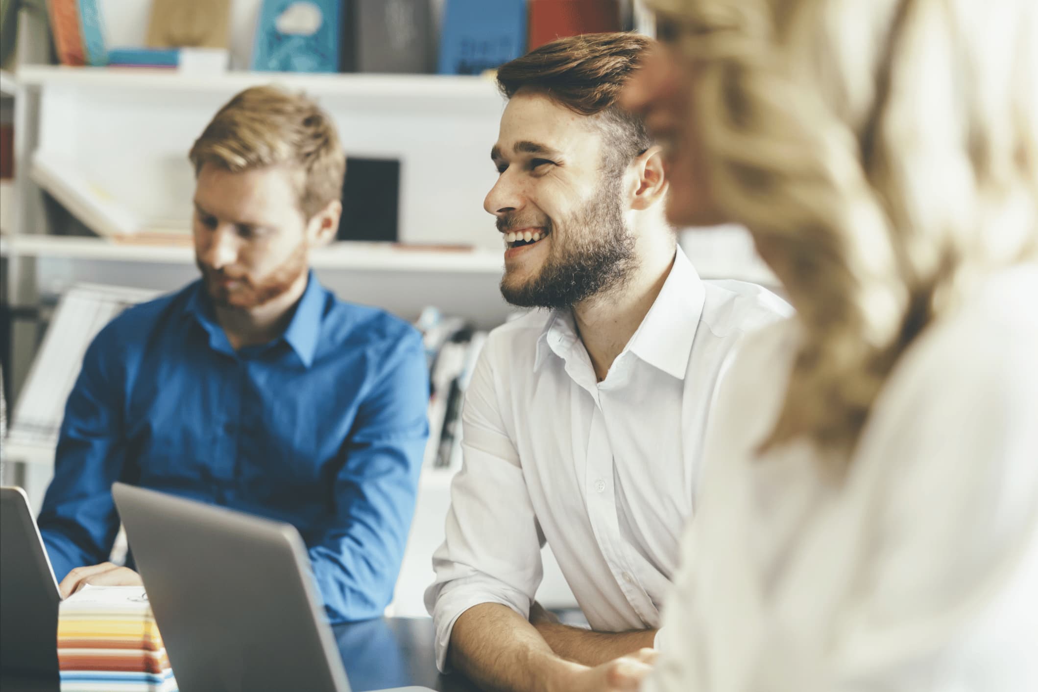 Close up of a man sitting at a table and smiling with his colleagues.