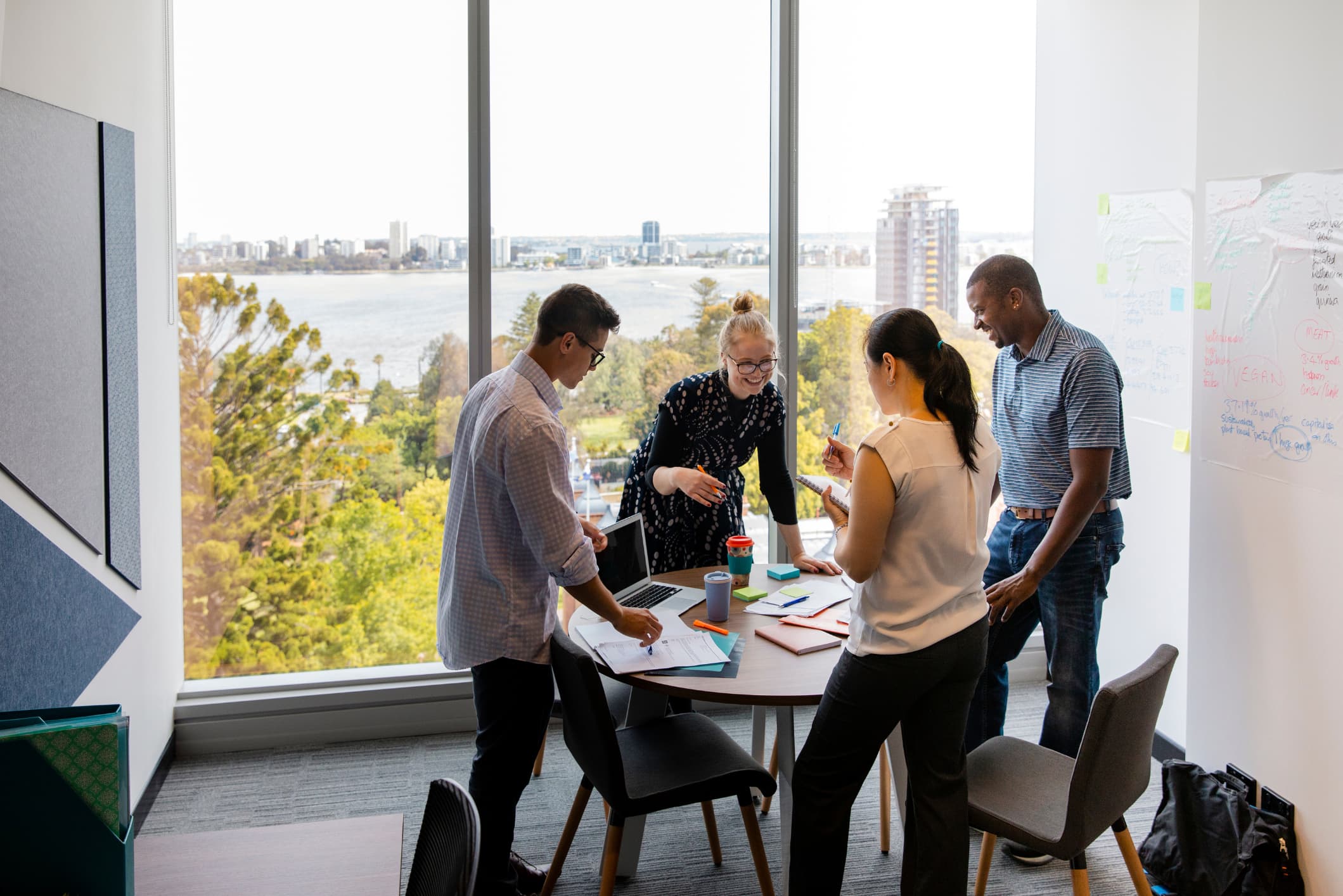 Four colleagues standing around a round table talking.