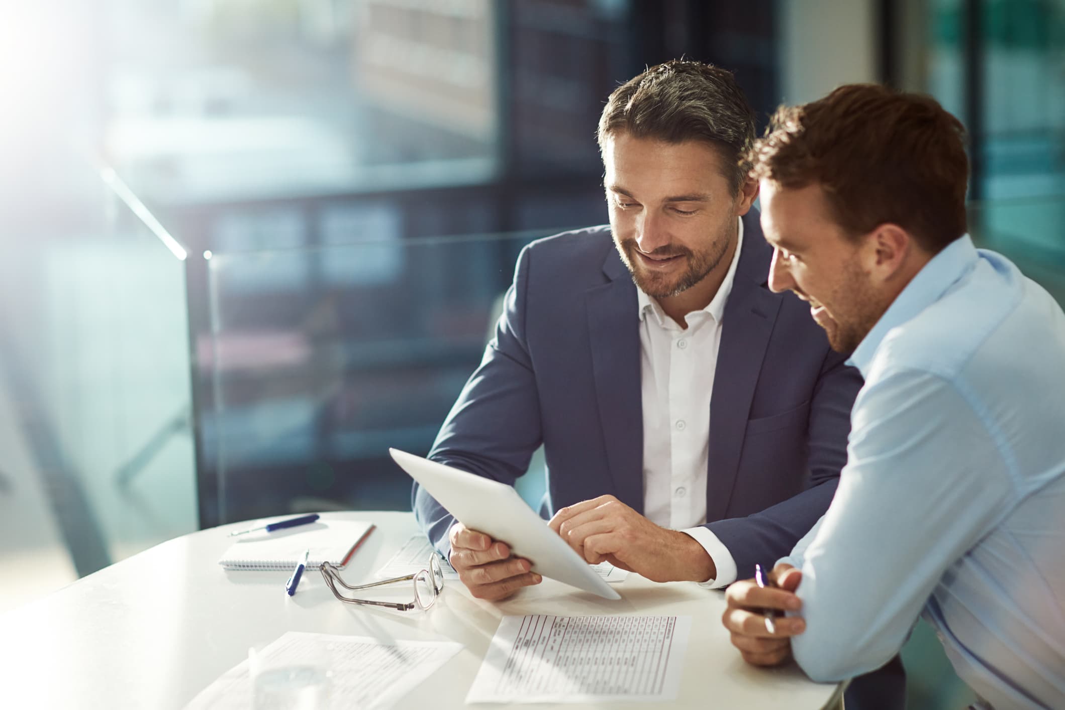 Two businessmen sitting at a table going over papers.
