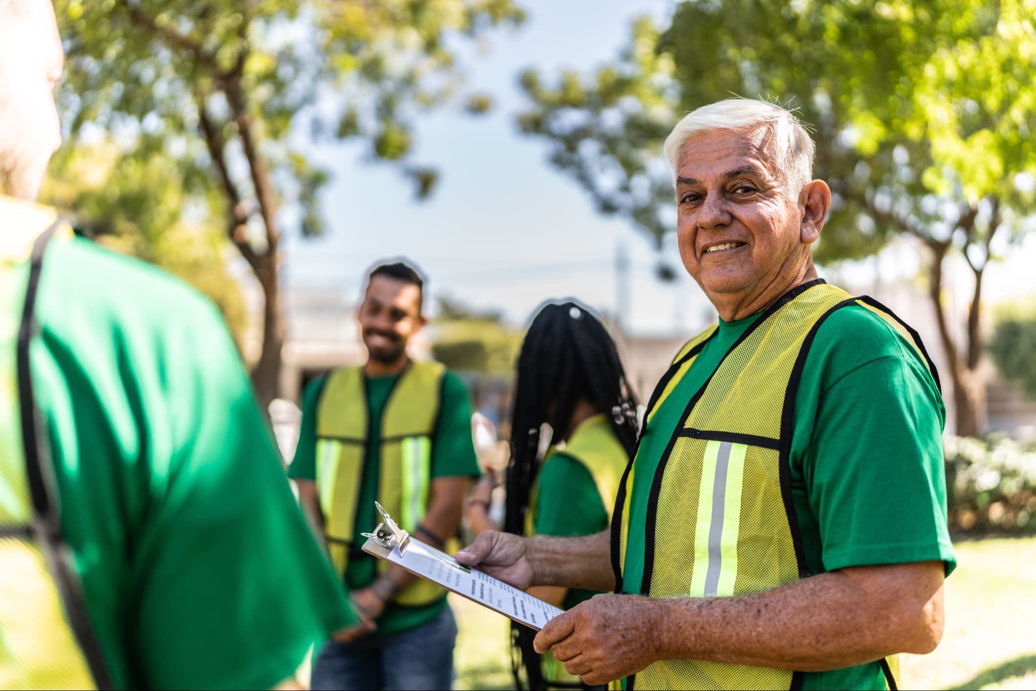 Portrait of a senior man holding a clipboard while volunteering at a park.